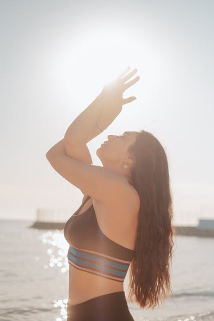 Woman meditating in a serene pose by a calm lake at sunrise